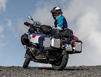 Das Bild zeigt eine vollausgestattete Reiseenduro, eine BMW R 1300 GS Adventure, mit Fahrer auf einem Schotterhügel.