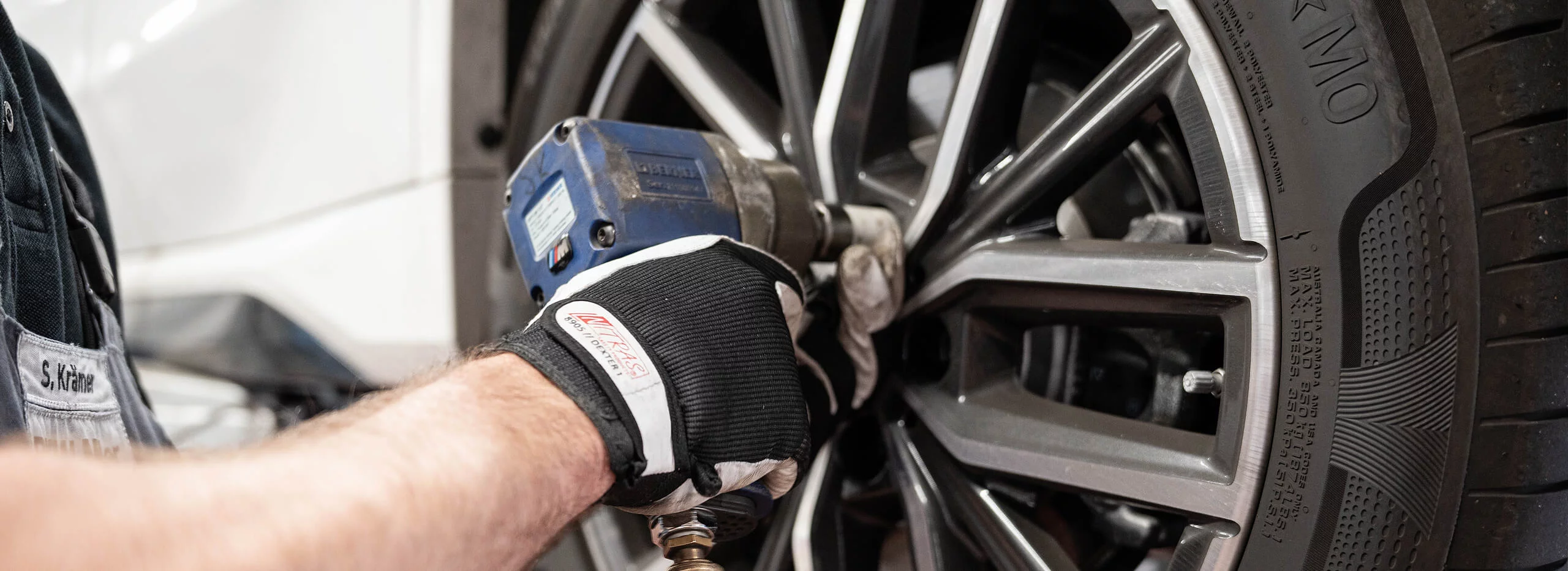 Ein Mechaniker zieht mit einem Schlagschrauber eine Radmutter an einem Reifen fest.