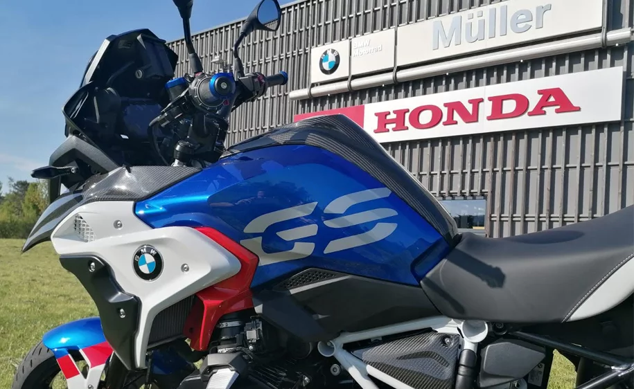 Blaues BMW GS Motorrad vor dem Autohaus Müller mit BMW und Honda Logos