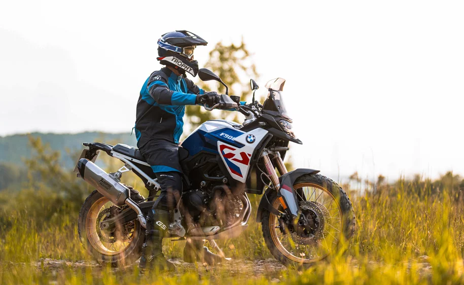 Motorradfahrer auf einer blau-weißen BMW F 900 GS Enduro auf einem Feldweg