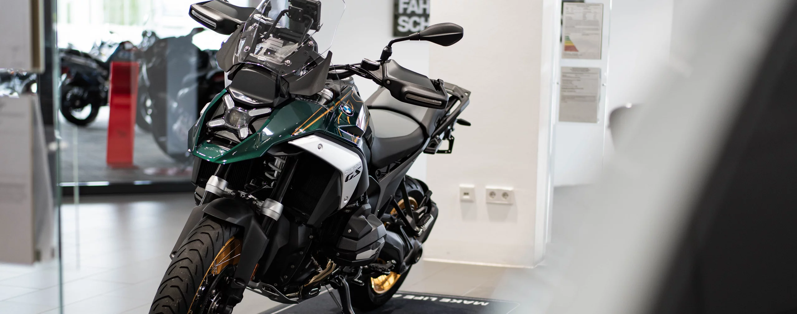 Grünes und schwarzes BMW GS Motorrad in einem Showroom mit goldenen Akzenten
