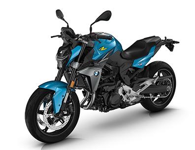  Auf dem Bild ist eine BMW F 900 R abgebildet, ein mittelgroßes, hellblaues und gelbes Motorrad, das auf einem weißen Hintergrund steht.  Das Motorrad ist in einem hellen, sonnigen Licht und steht seitlich zur Kamera. Es ist sauber und glänzt, als wäre es brandneu.