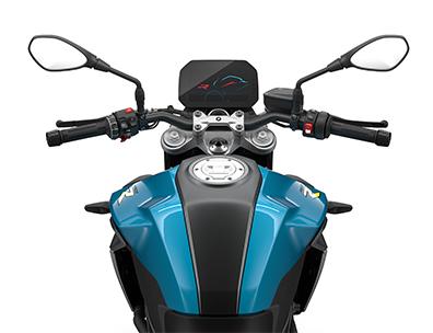  Auf dem Bild ist eine BMW F 900 R abgebildet, ein mittelgroßes, hellblaues und gelbes Motorrad, das auf einem weißen Hintergrund steht.  Das Bild zeigt eine Nahaufnahme der Front des Motorrads, von der Perspektive eines Fahrers. Man sieht den Lenker mit Spiegeln, das beleuchtete Armaturenbrett, das BMW-Logo und den Tank. Es ist sauber und glänzt, als wäre es brandneu.