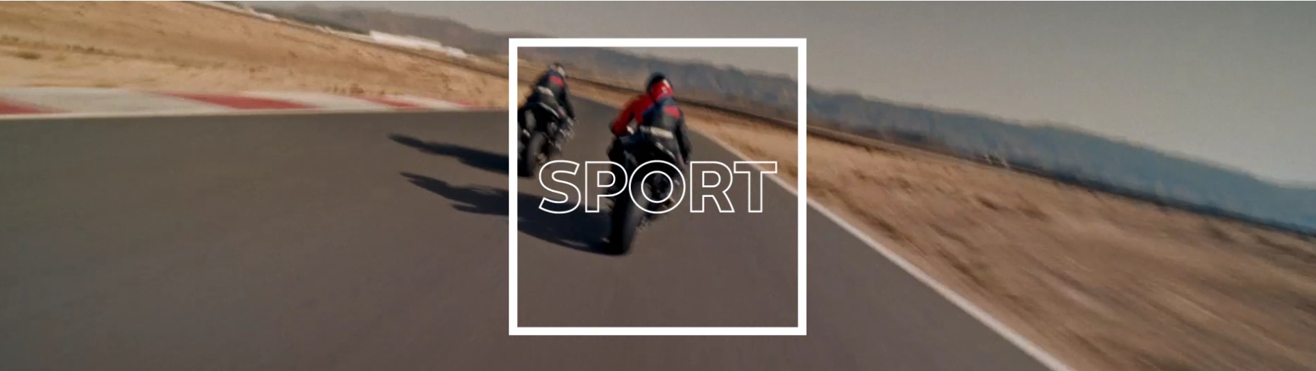 Das Bild zeigt zwei Motorräder auf einer Rennstrecke, wobei die Rennstrecke und die Umgebung unscharf sind, um Geschwindigkeit zu vermitteln. Im Vordergrund, über das gesamte Bild, liegt ein weißer, rechteckiger Rahmen. Innerhalb dieses Rahmens, in Großbuchstaben und in weißer Farbe, steht das Wort „SPORT“.